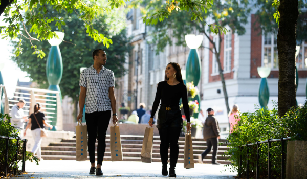 A photo of a man and woman walking down the street with shopping bags.