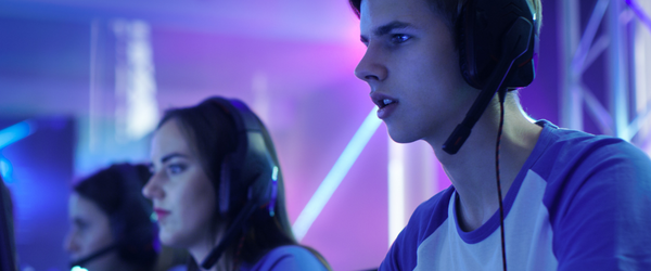 A young boy with headphones on sat at a desk with a large screen