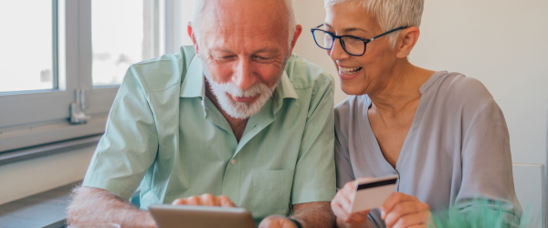 Tow older people looking at a laptop, smiling